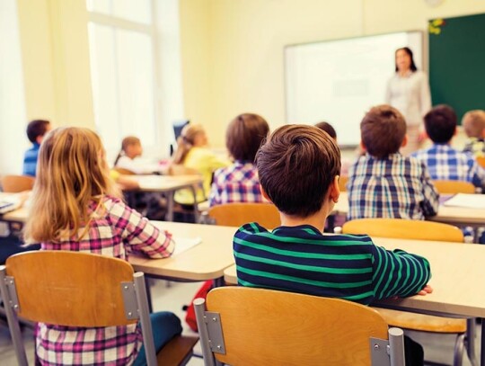 group of school kids and teacher in classroom