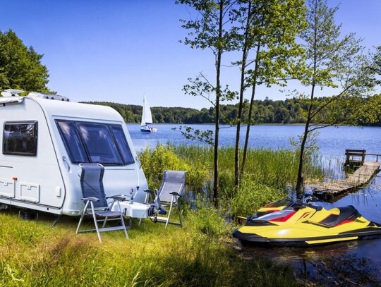 Vacations in Poland - Summer view of camper trailer on the shore of the Drawsko lake