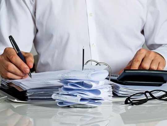 Businessman Calculating Invoice At Desk