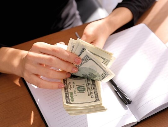 Woman counting dollar banknotes at table