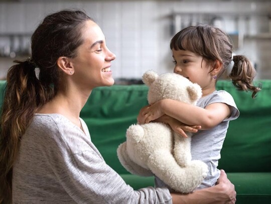 Smiling mother hugging cute daughter showing love and care