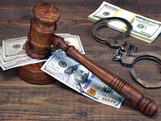 Dollar Cash, handcuffs and judge gavel on wood table