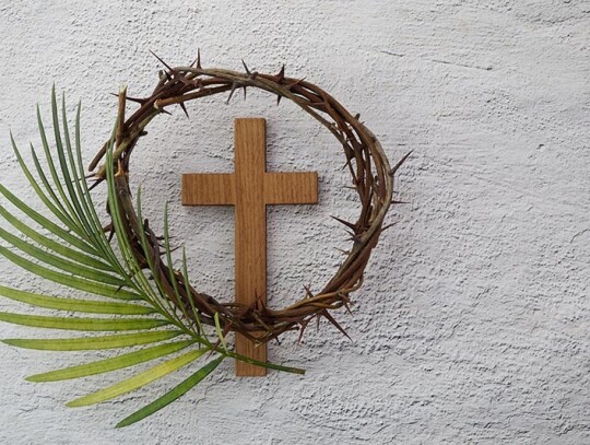 Palm sunday background. Cross and palm on grey background.