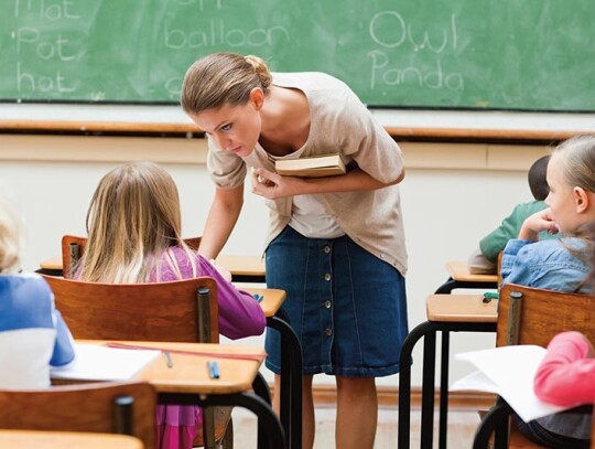 Teacher next to pupils desk