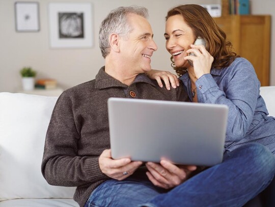 Happy middle aged couple seated on white couch